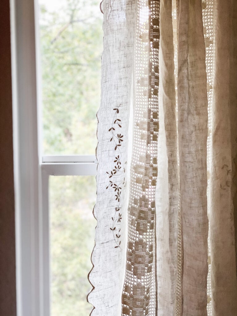 Vintage linen tablecloth that has been turned into a curtain - hanging in window