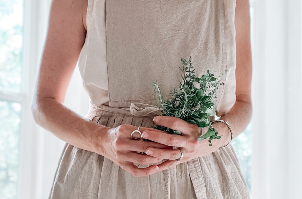 woman's hands holding freshly harvested herb sprigs - standing in front of a window