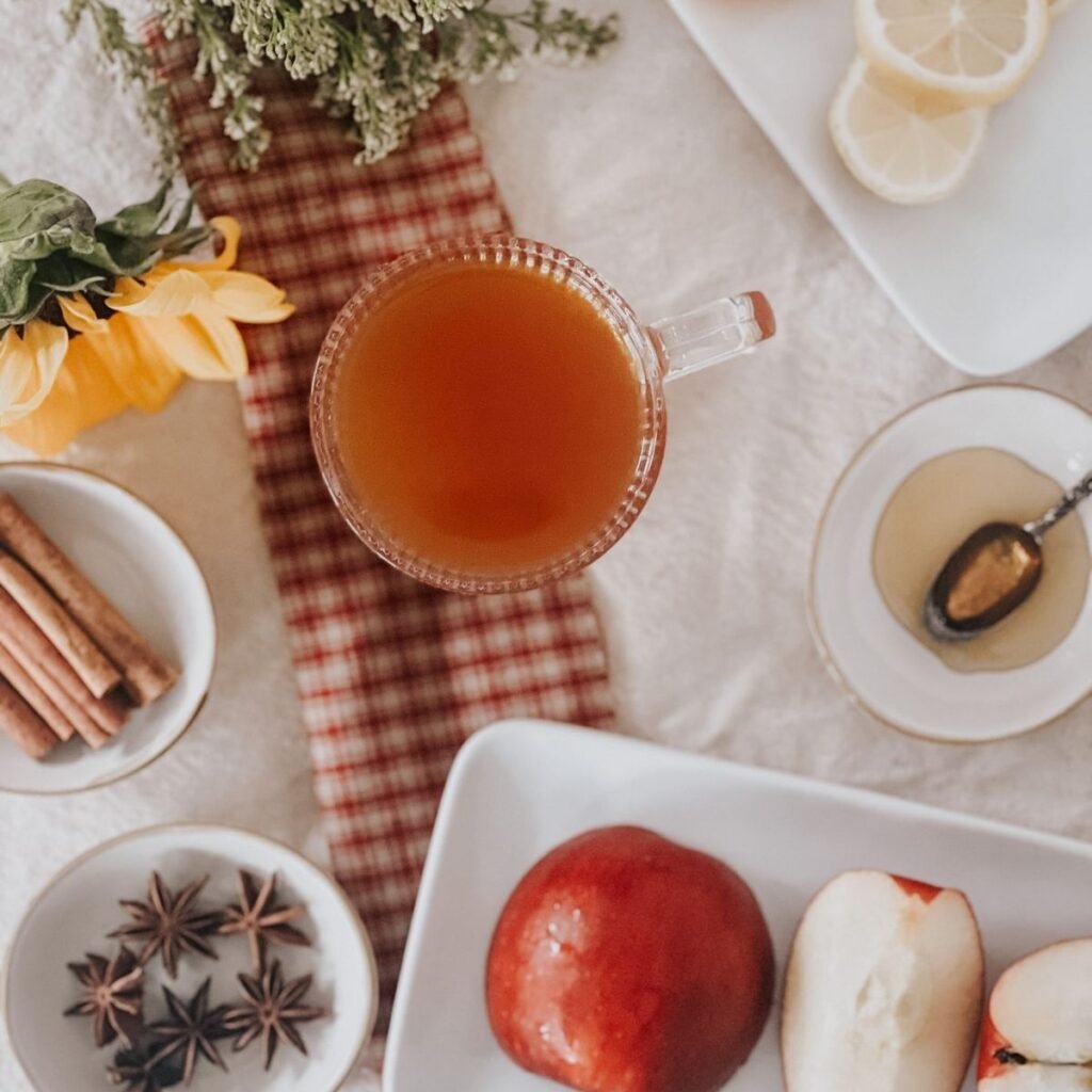 Overhead view of the apple cider in a glass mug on a table surrounded by the ingredients.