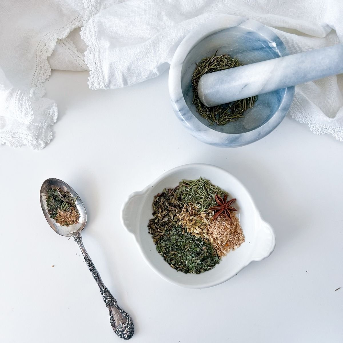 Mortar and Pestle with a bowl of herbs on a white background.
