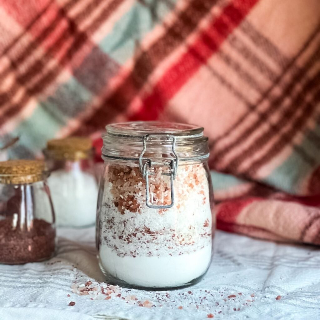 A glass jar filled with the layers of the ingredients to make fizzing peppermint bath salts.
