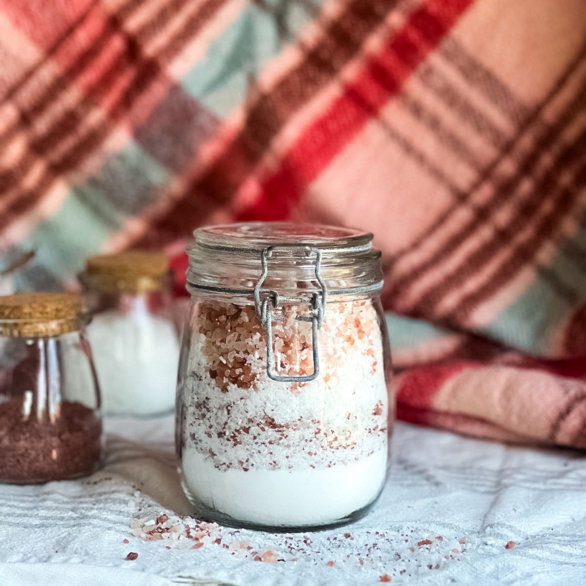 A glass jar filled with the layers of the ingredients to make fizzing peppermint bath salts.