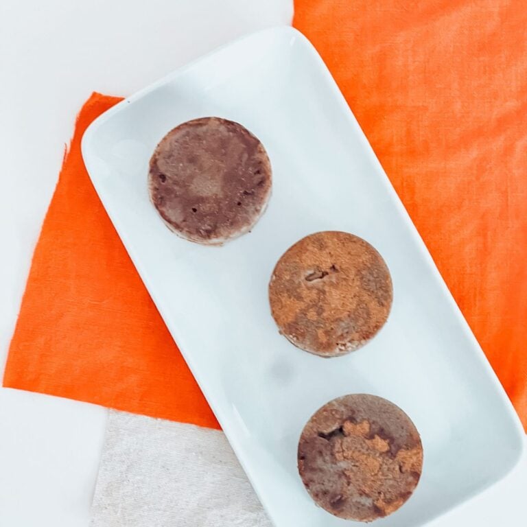 pumpkin spice sugar scrub. bars on a white rectangular plate on top of an orange background.