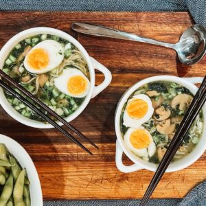 Bowls of ramen soup on top of a wooden table.
