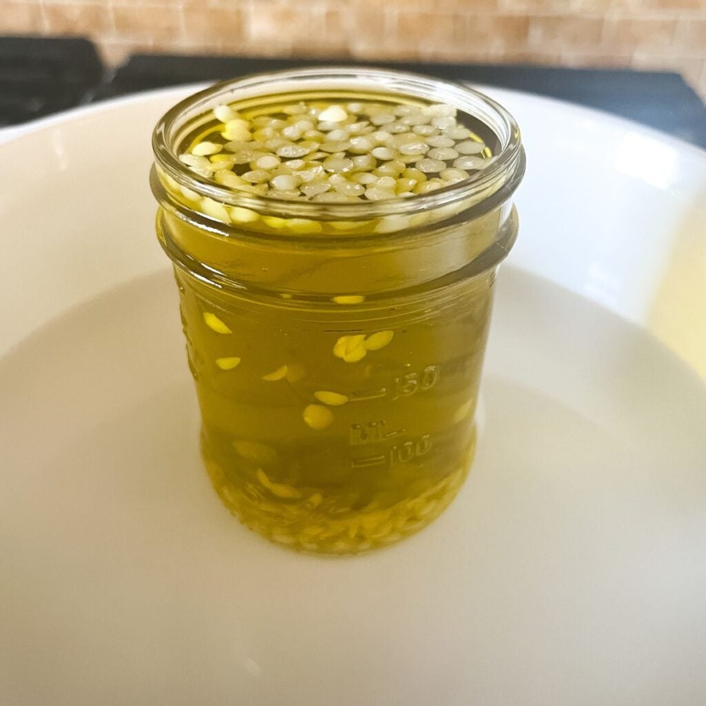 A close up of the mason jar filled with the lavender-infused olive oil and the beeswax pellets.